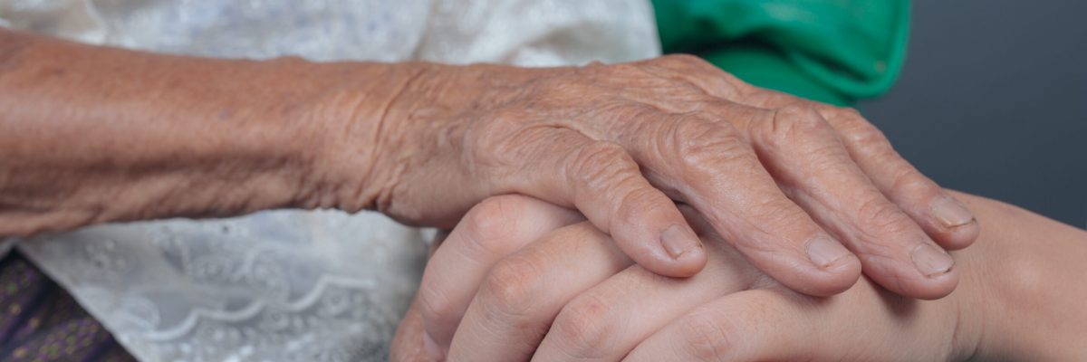 Young woman holding an elderly woman's hand.